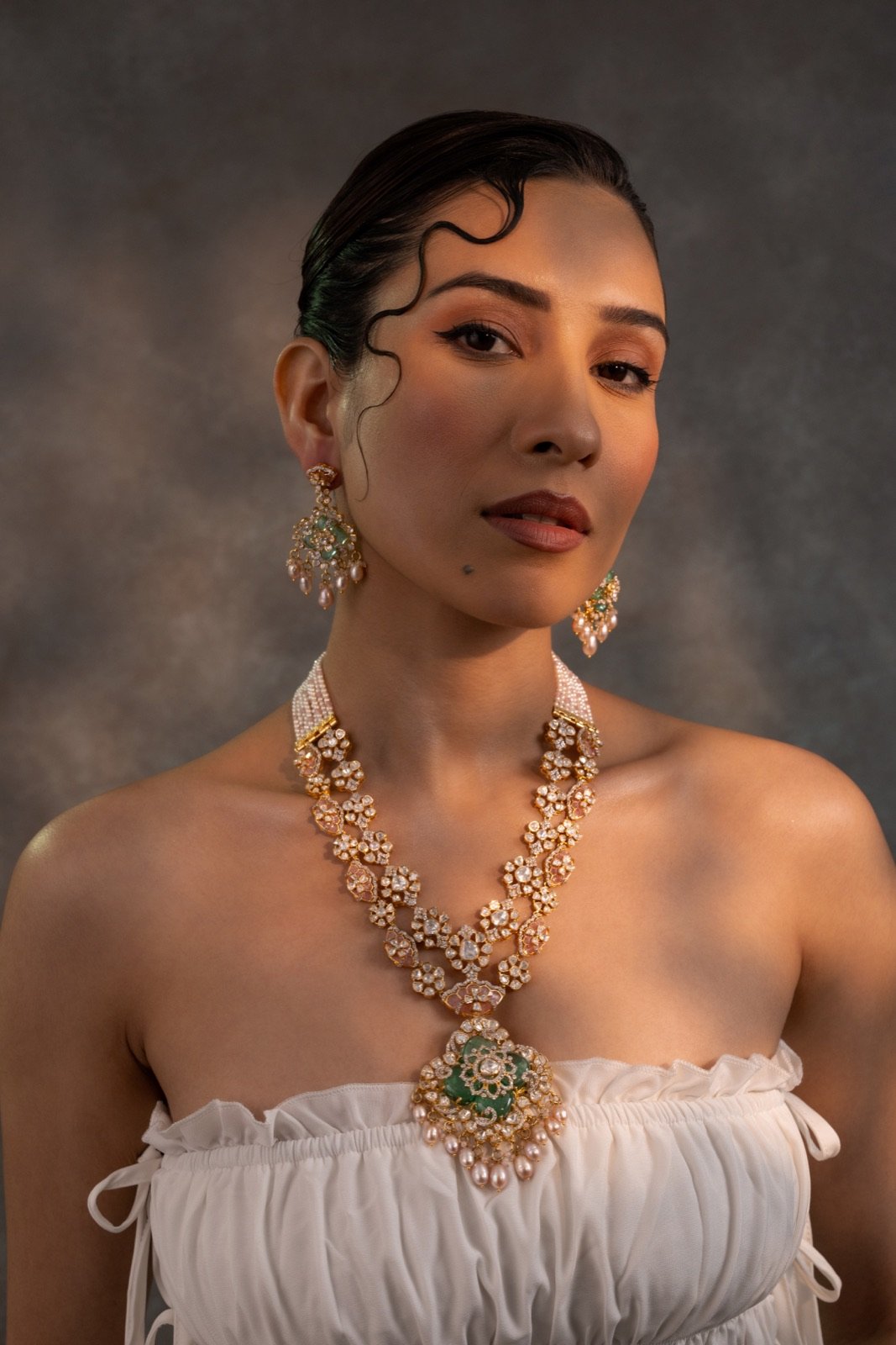 Long necklace with matching earrings worn against a dark backdrop